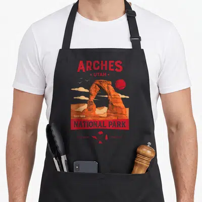 National backpacking apron - Red rock arch with Arches Utah text and camping icons preserve protect — shown on a black cotton canvas apron against a white background