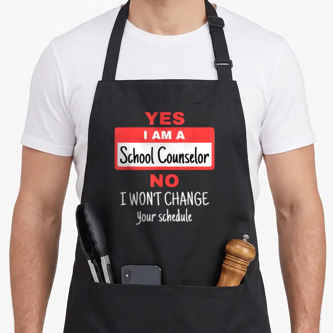 School change apron - Red and white text reading Yes I am a School Counselor No I won't change your schedule — shown on a black cotton canvas apron against a white background