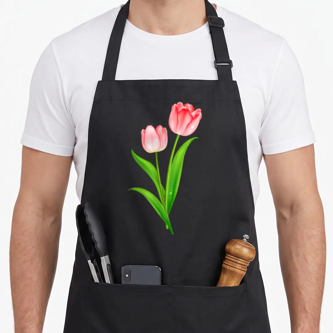 Beautiful tulip apron - Two pink tulips with green leaves and water droplets crossing at stems — shown on a black cotton canvas apron against a white background