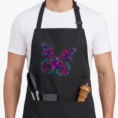 Flower thyroid apron - Butterfly shape made of small butterflies pink flowers and purple blue ribbon — shown on a black cotton canvas apron against a white background