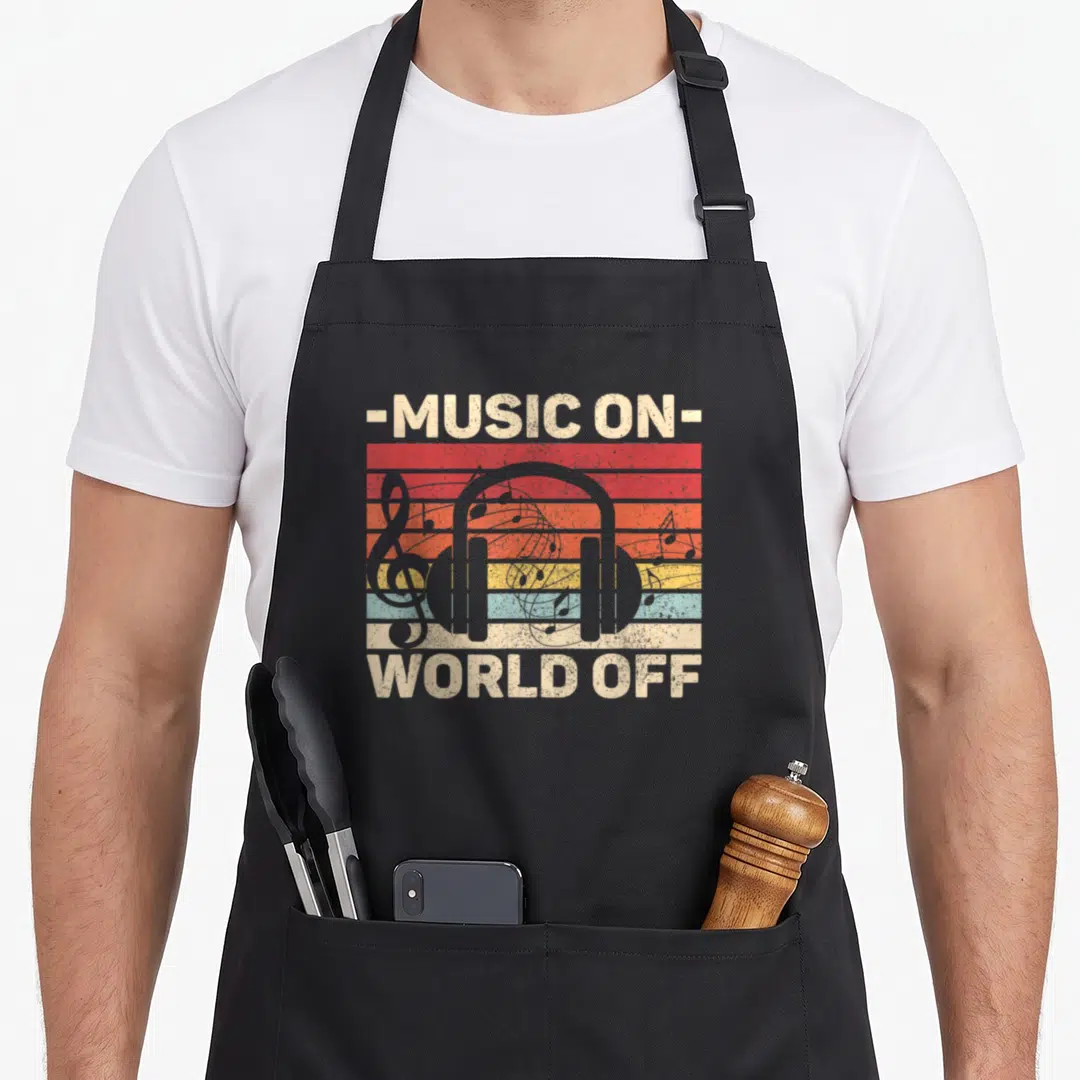 Outfit music apron - Retro graphic of grey headphones and notes over red orange yellow blue beige stripes with text — shown on a black cotton canvas apron against a white background