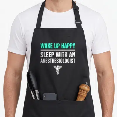 Wake doctor apron - WAKE UP HAPPY SLEEP WITH AN ANESTHESIOLOGIST text and caduceus symbol in mint and white — shown on a black cotton canvas apron against a white background