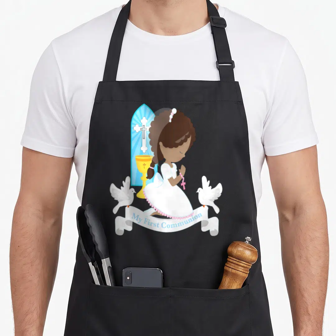 African communion aprons - Cartoon girl kneeling in prayer with doves chalice and My First Communion ribbon — shown on a black cotton canvas apron against a white background