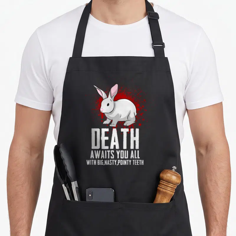 Death rabbit apron - White rabbit on red splatter with text DEATH AWAITS YOU ALL WITH BIG NASTY POINTY TEETH — shown on a black cotton canvas apron against a white background
