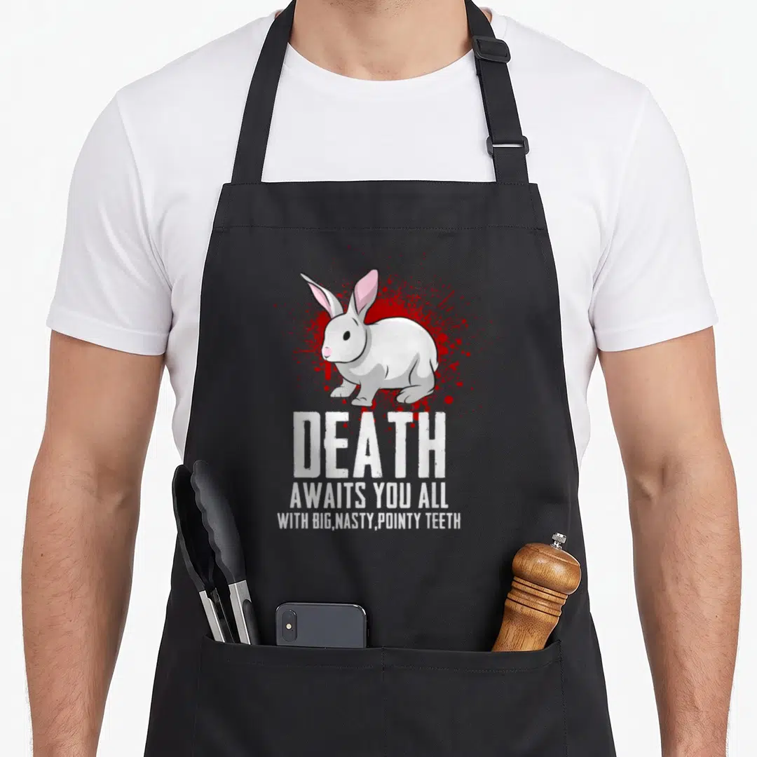 Death rabbit apron - White rabbit on red splatter with text DEATH AWAITS YOU ALL WITH BIG NASTY POINTY TEETH — shown on a black cotton canvas apron against a white background
