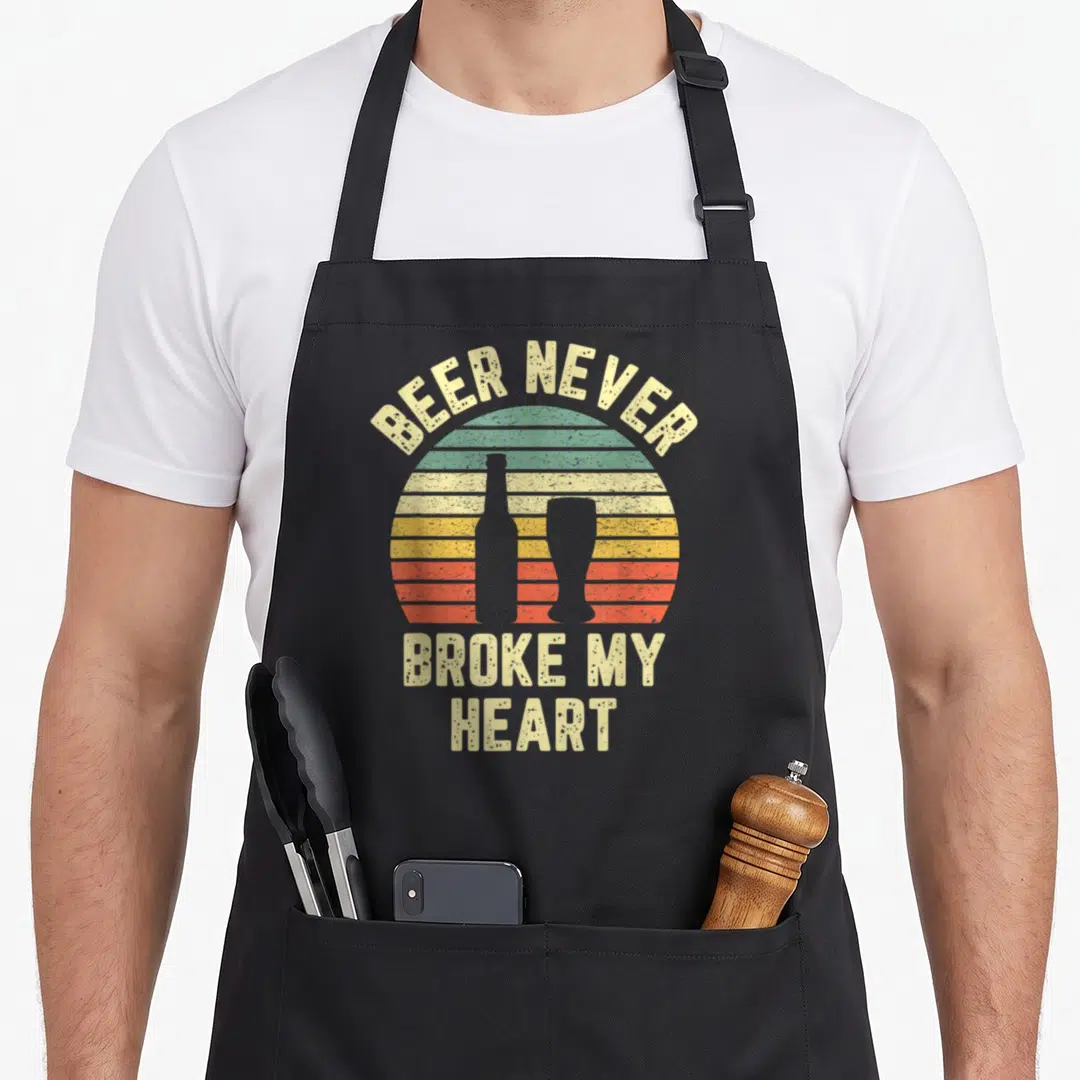 Broke drinking beer apron - Retro striped sunset with beer bottle silhouette and text BEER NEVER BROKE MY HEART — shown on a black cotton canvas apron against a white background