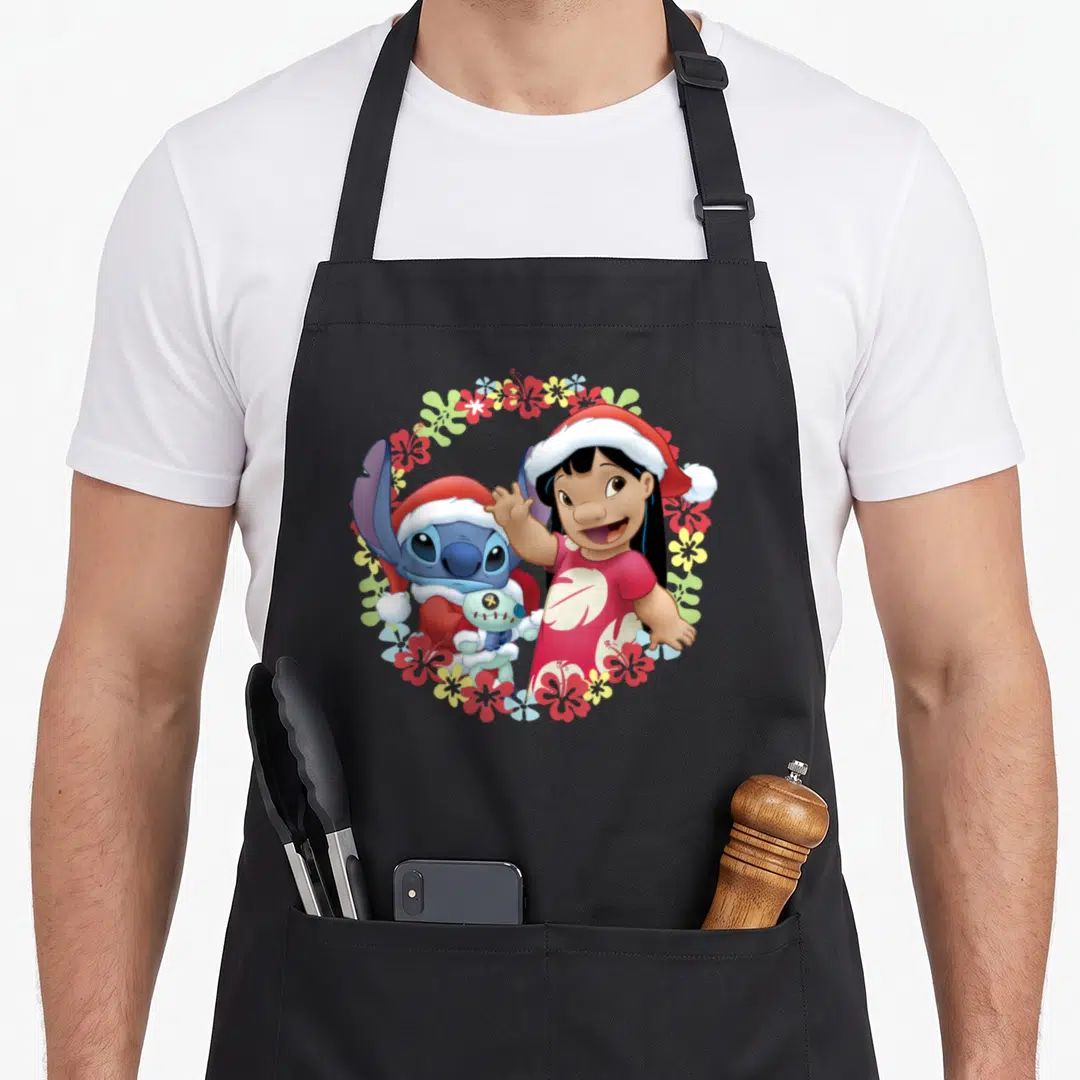 Hawaiian christmas apron - Lilo and Stitch in Santa hats holding Scrump inside a red blue yellow and white tropical — shown on a black cotton canvas apron against a white background