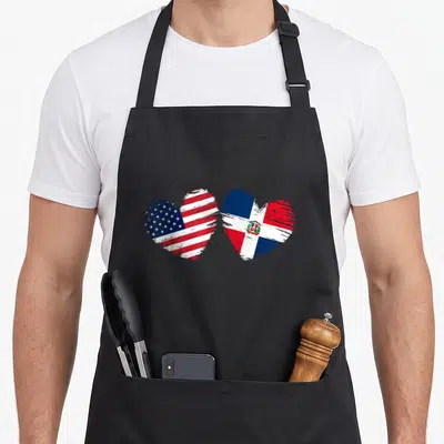 Dominican american flag apron - Two hearts filled with red white and blue flag patterns in distressed brushstrokes — shown on a black cotton canvas apron against a white background