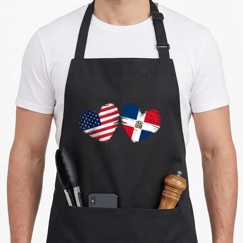 Dominican american flag apron - Two hearts filled with red white and blue flag patterns in distressed brushstrokes — shown on a black cotton canvas apron against a white background