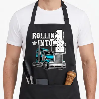 4th semi truck apron - Blue semi-truck graphic with white ROLLIN INTO 4 text and star icon — shown on a black cotton canvas apron against a white background