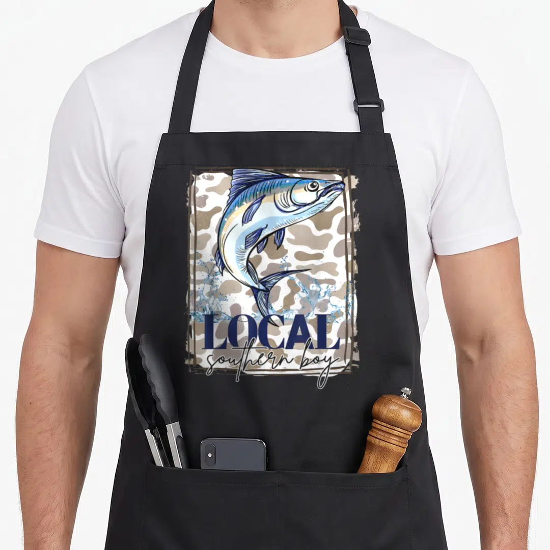 Local southern aprons - Jumping fish on tan white camo with navy LOCAL southern boy text — shown on a black cotton canvas apron against a white background