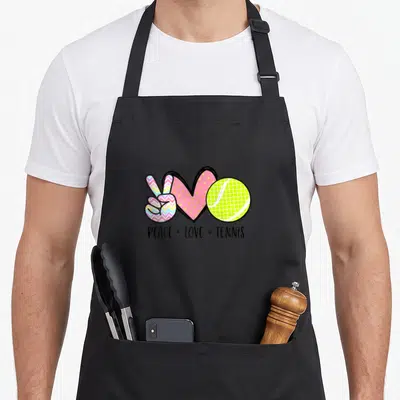 Tennis pastel aprons - Peace sign chevron pattern, pink polka dot heart, lime tennis ball, PEACE LOVE TENNIS text — shown on a black cotton canvas apron against a white background