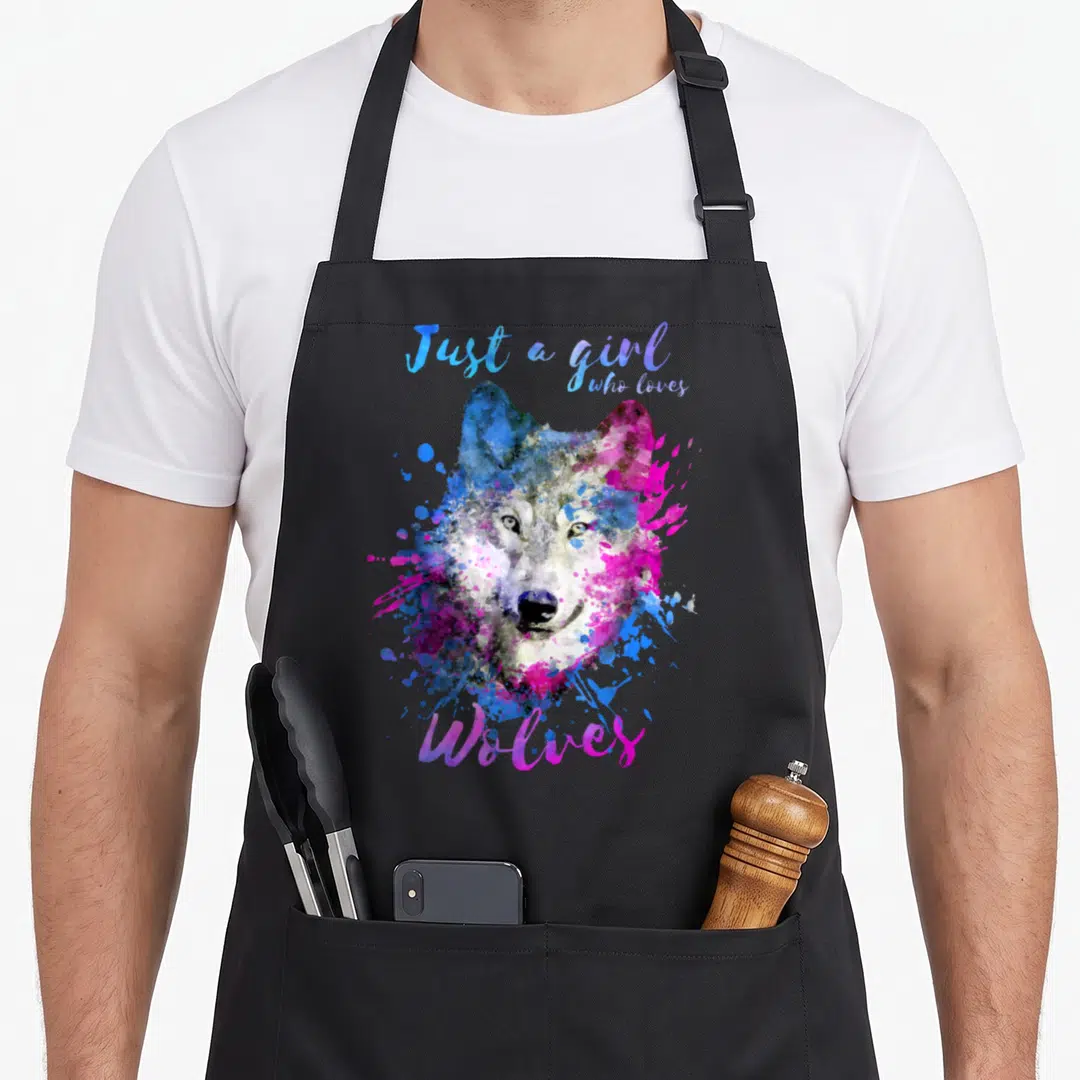 Wolve splash aprons - Watercolor wolf head in blue and pink splashes with text Just a girl who loves Wolves — shown on a black cotton canvas apron against a white background