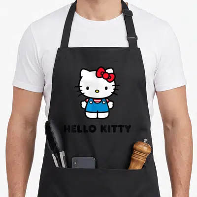 General character aprons - Cartoon Hello Kitty in blue overalls with red bow and black text below — shown on a black cotton canvas apron against a white background