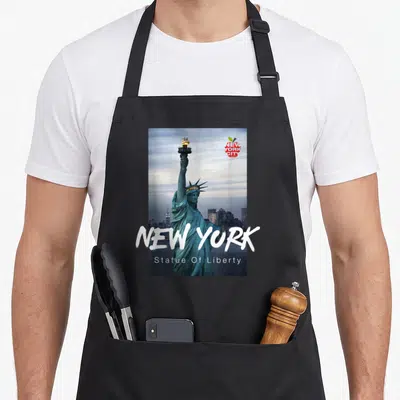 Funny statue new york apron - Statue of Liberty photo with NEW YORK text and red apple logo on black apron — shown on a black cotton canvas apron against a white background