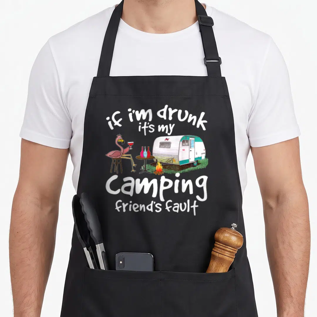 Drunk flamingo apron - Pink flamingo at table with camper trailer and white sarcastic text — shown on a black cotton canvas apron against a white background