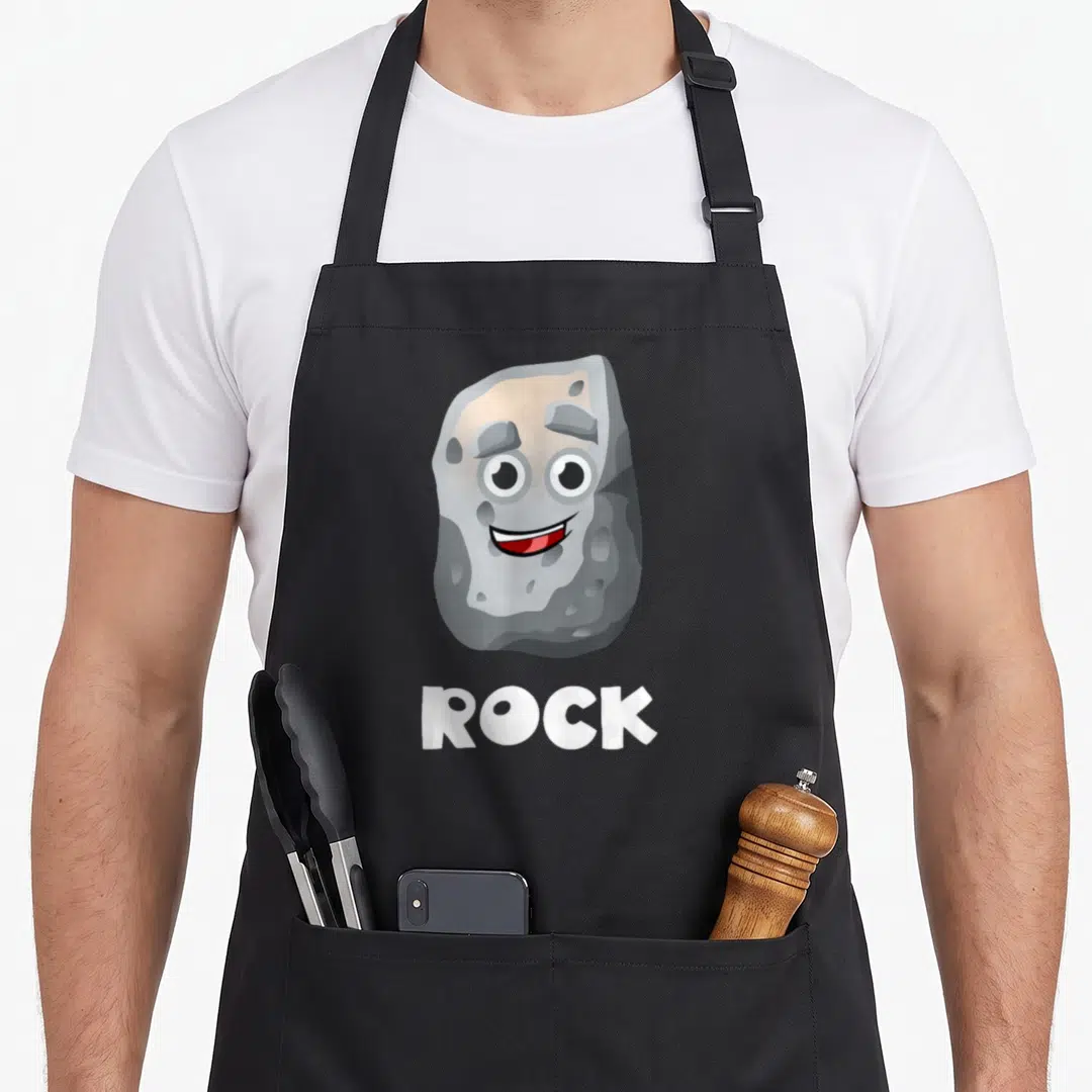 Halloween paper apron - Cartoon grey rock with face and white ROCK text below — shown on a black cotton canvas apron against a white background