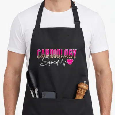 Cardiology squad nurse apron - Pink CARDIOLOGY text with leopard print bottom, white Squad script, heartbeat line, pink — shown on a black cotton canvas apron against a white background