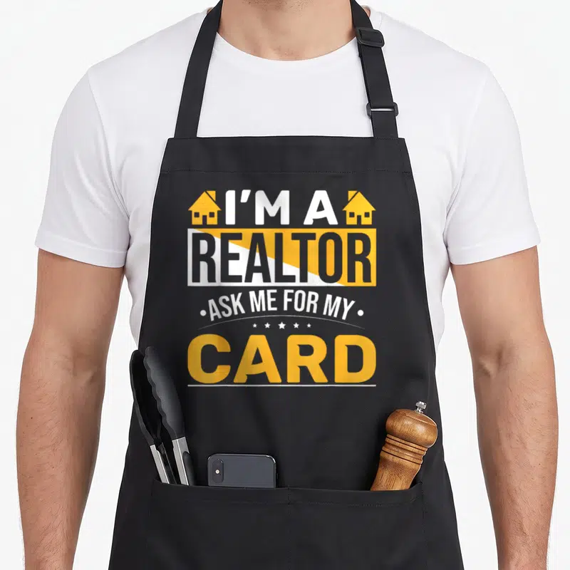 Card agent apron - Stacked yellow and white text I'M A REALTOR ASK ME FOR MY CARD with two houses and five stars — shown on a black cotton canvas apron against a white background