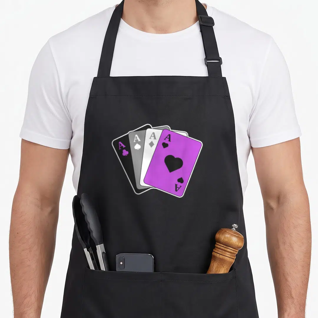 Playing pride apron - Four fanned playing cards in purple, black, grey, and white showing Ace letters — shown on a black cotton canvas apron against a white background