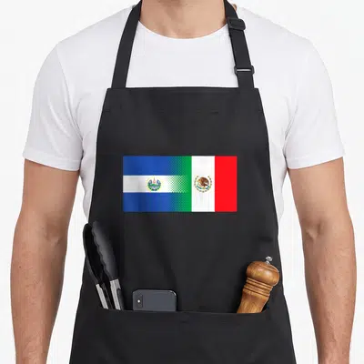 Salvadorian flag el cook apron - Two flags merging with halftone dots in blue white green and red — shown on a black cotton canvas apron against a white background
