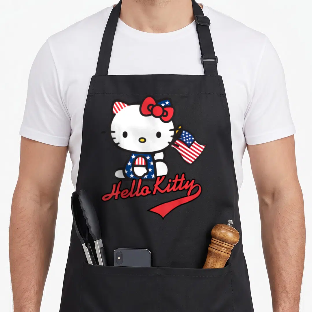 Cute american flag apron - Hello Kitty holding US flag with red white blue stars and script text — shown on a black cotton canvas apron against a white background