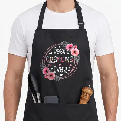 Grandma announcement mother's day aprons - Best Grandma Ever text in pink circle with watercolor flowers and hearts — shown on a black cotton canvas apron against a white background