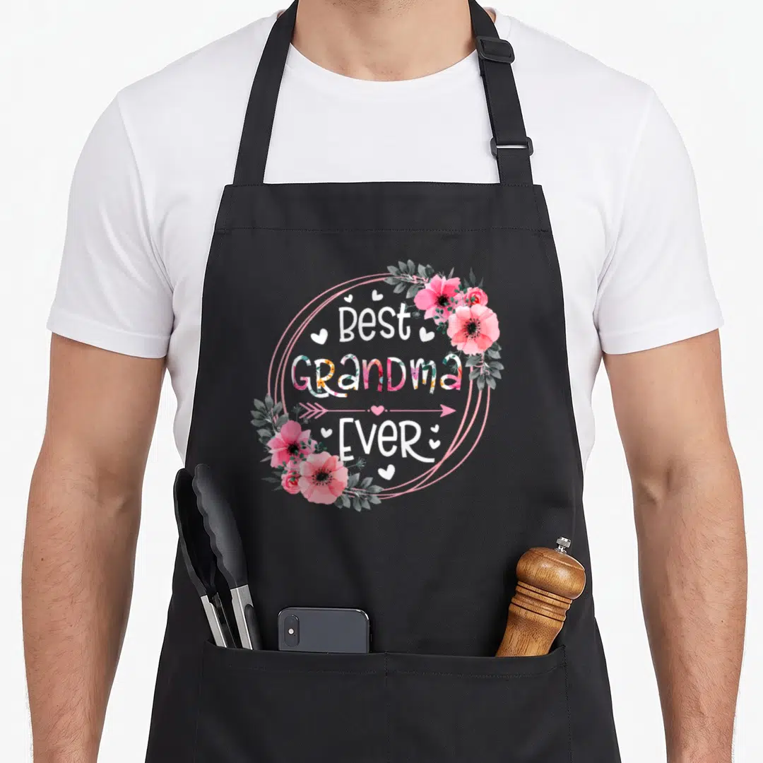 Grandma announcement mother's day aprons - Best Grandma Ever text in pink circle with watercolor flowers and hearts — shown on a black cotton canvas apron against a white background