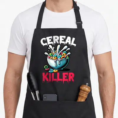Funny killer cereal apron - Dripping CEREAL KILLER text above and below a bowl of colorful ring cereal with milk — shown on a black cotton canvas apron against a white background