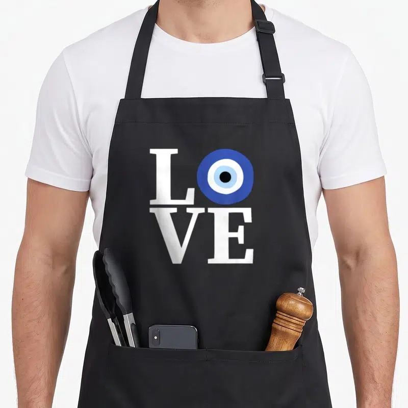 Pride evil greek aprons - White LOVE text with blue evil eye replacing O on black fabric — shown on a black cotton canvas apron against a white background