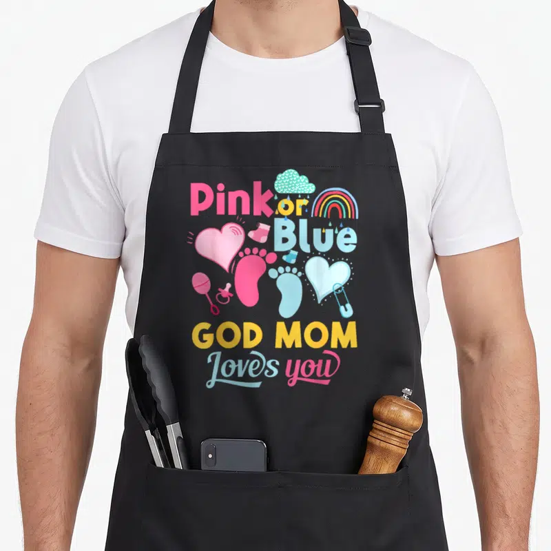God apron or apron - Pink or Blue God Mom Loves you text with hearts and baby icons in pink blue yellow — shown on a black cotton canvas apron against a white background