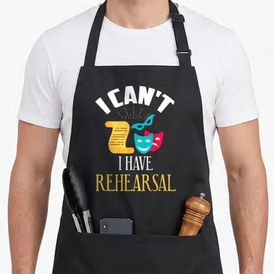 Probe theatre apron - I can't I have rehearsal text with theater masks and scroll on black bib — shown on a black cotton canvas apron against a white background