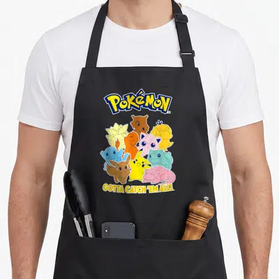 Pok mon novelty apron - Pokemon logo, colorful creature cluster, gotta catch em all slogan — shown on a black cotton canvas apron against a white background