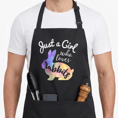 Rabbit custom pet apron - Colorful watercolor rabbit silhouette with white and grey text reading Just a Girl who loves — shown on a black cotton canvas apron against a white background