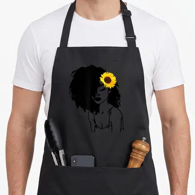 Afro african print apron - Black line art woman with yellow sunflower in afro hair — shown on a black cotton canvas apron against a white background