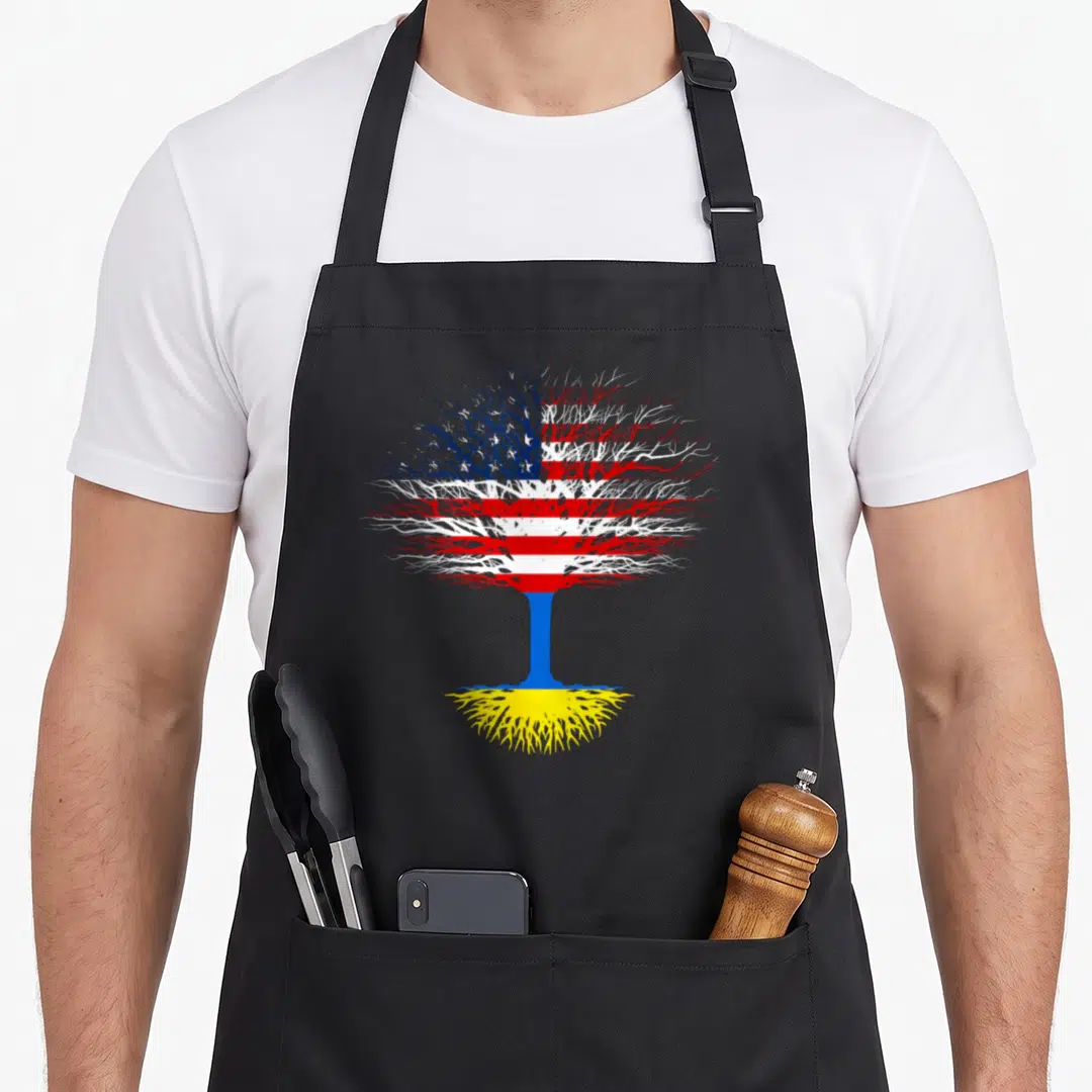 Ukraine tree apron - Stylized tree with US flag canopy, blue trunk, and yellow roots on black background — shown on a black cotton canvas apron against a white background