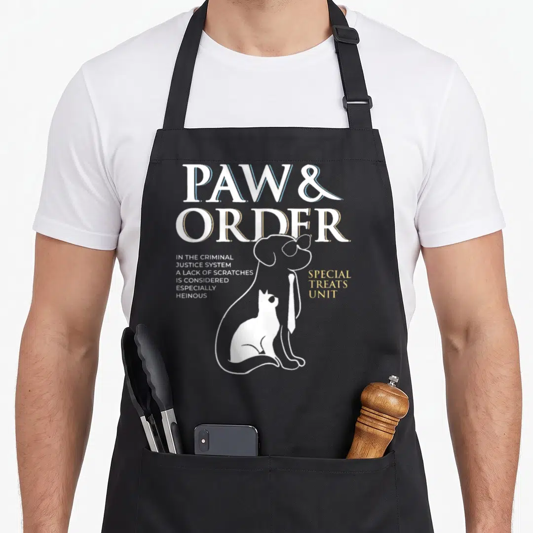 Paw dog training apron - Line art dog wearing tie with cat, PAW & ORDER text and criminal justice system quote — shown on a black cotton canvas apron against a white background