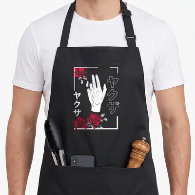 Japanese best break ever apron - White hand, red roses, vertical Japanese text, partial frame, line art — shown on a black cotton canvas apron against a white background