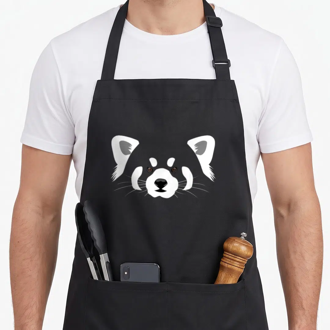 Funny panda apron - Minimalist grey white black raccoon head illustration centered on fabric — shown on a black cotton canvas apron against a white background