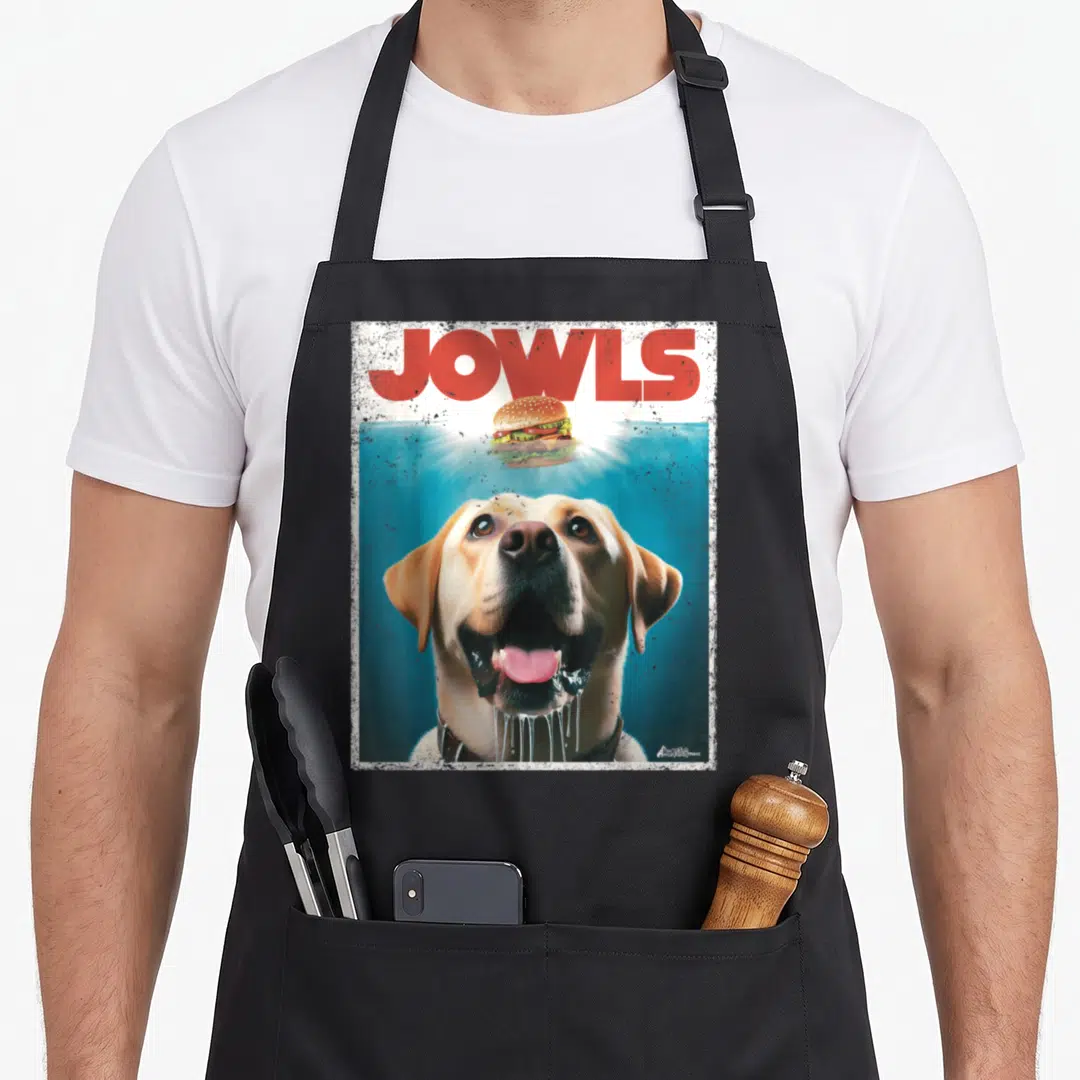 Lab jowl labrador apron - Photo of yellow lab looking up at floating burger under red JOWLS text with distressed white — shown on a black cotton canvas apron against a white background