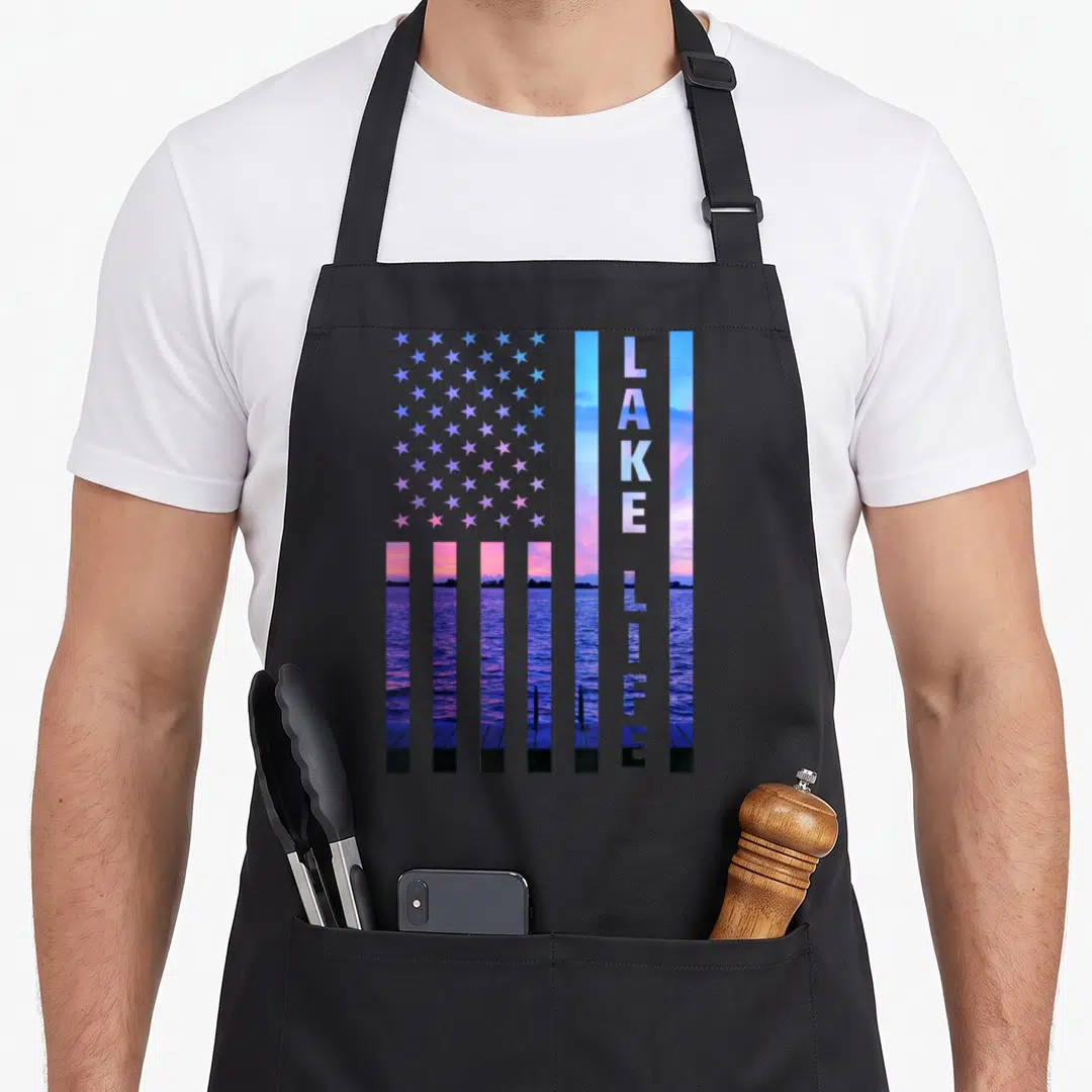 Dock american flag apron - USA flag shape filled with lake sunset photo and vertical LAKE LIFE text in blue and purple — shown on a black cotton canvas apron against a white background