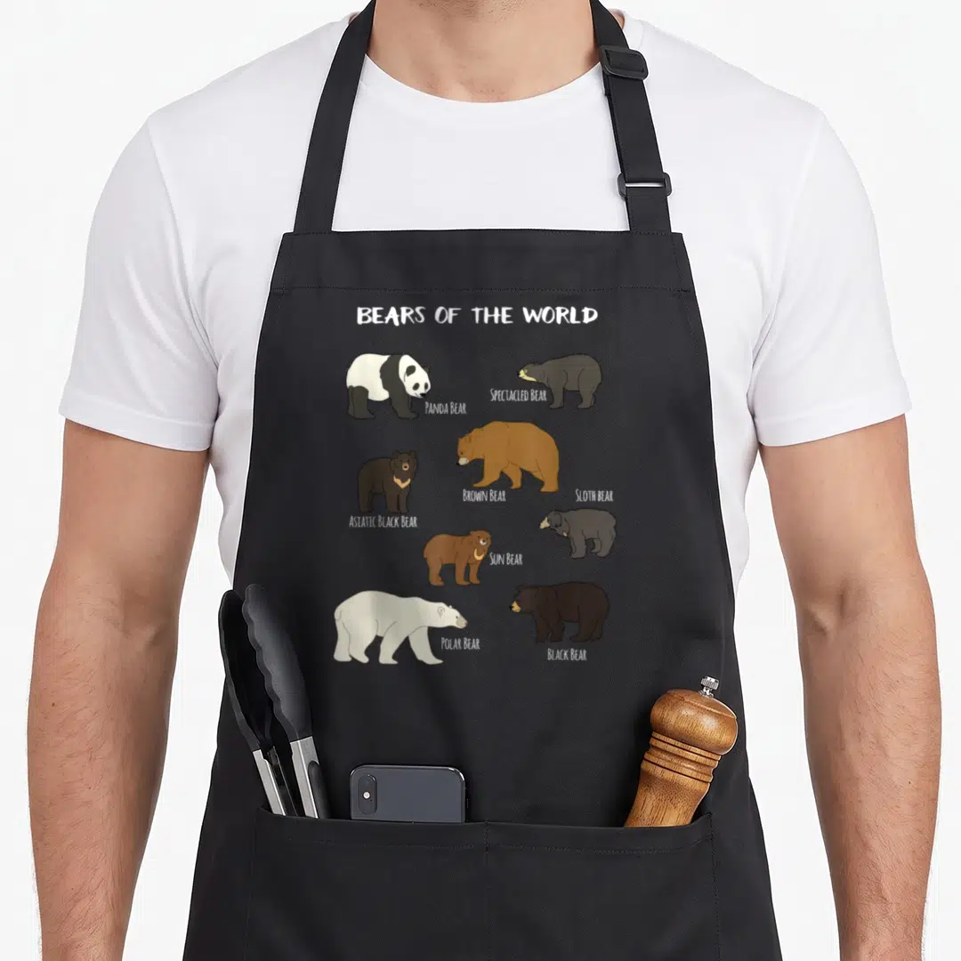 Polar bear apron - Eight cartoon bears labeled Panda, Brown, Polar, and Black on a grey background — shown on a black cotton canvas apron against a white background