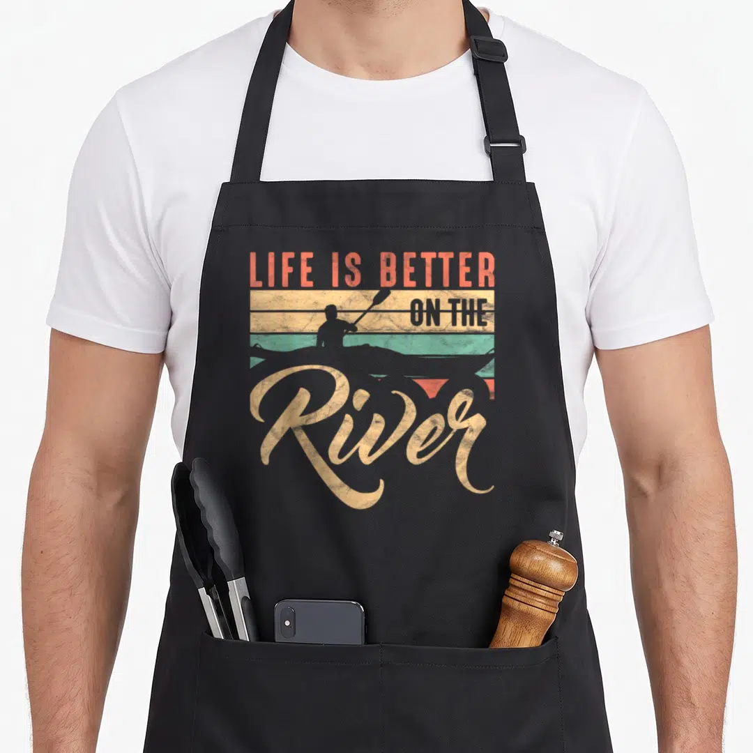Rowing green river apron - Retro kayaker silhouette against beige teal and red orange stripes with Life Is Better — shown on a black cotton canvas apron against a white background
