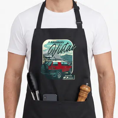 Cruiser iconic aprons - Retro red FJ Cruiser illustration with Faraway Vistas text and mountain landscape in rounded — shown on a black cotton canvas apron against a white background