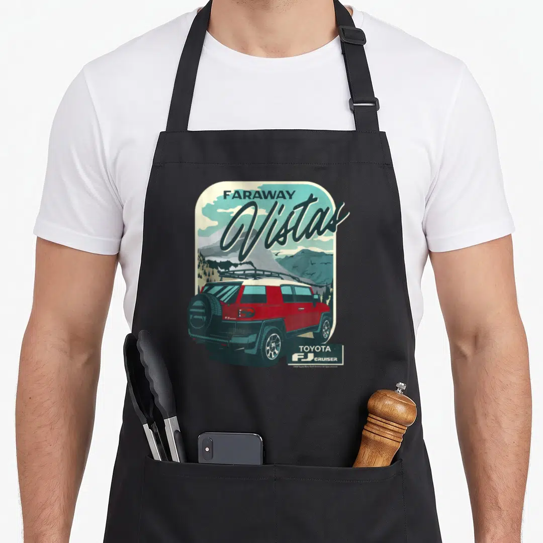 Cruiser iconic aprons - Retro red FJ Cruiser illustration with Faraway Vistas text and mountain landscape in rounded — shown on a black cotton canvas apron against a white background