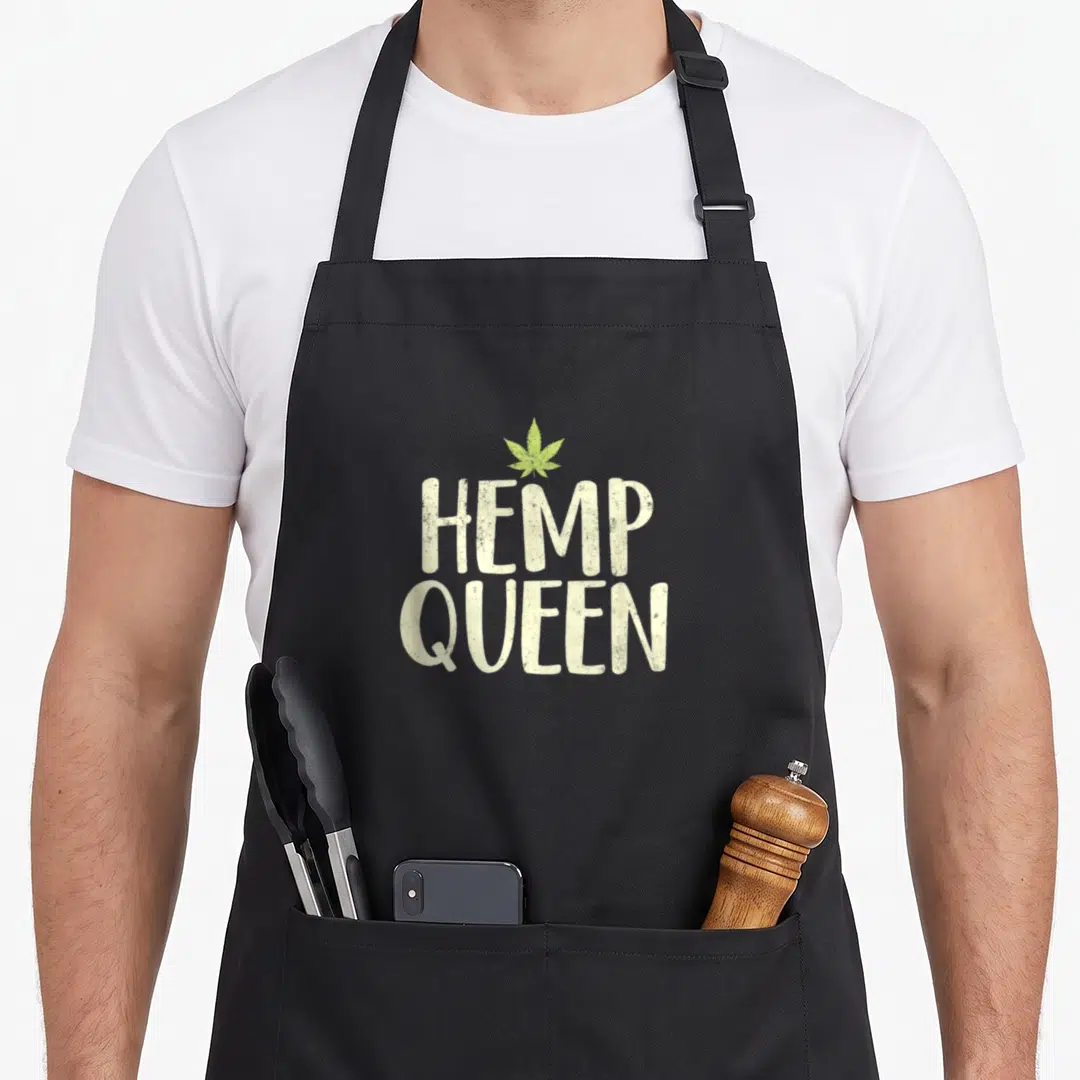 Queen hemp apron - Stacked HEMP QUEEN text with green cannabis leaf above — shown on a black cotton canvas apron against a white background