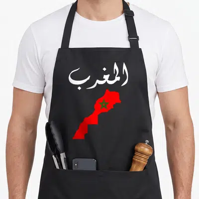 Morocco pride apron - White Arabic text above a red map of Morocco containing a green star — shown on a black cotton canvas apron against a white background