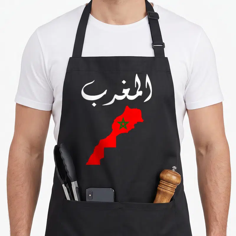 Morocco pride apron - White Arabic text above a red map of Morocco containing a green star — shown on a black cotton canvas apron against a white background