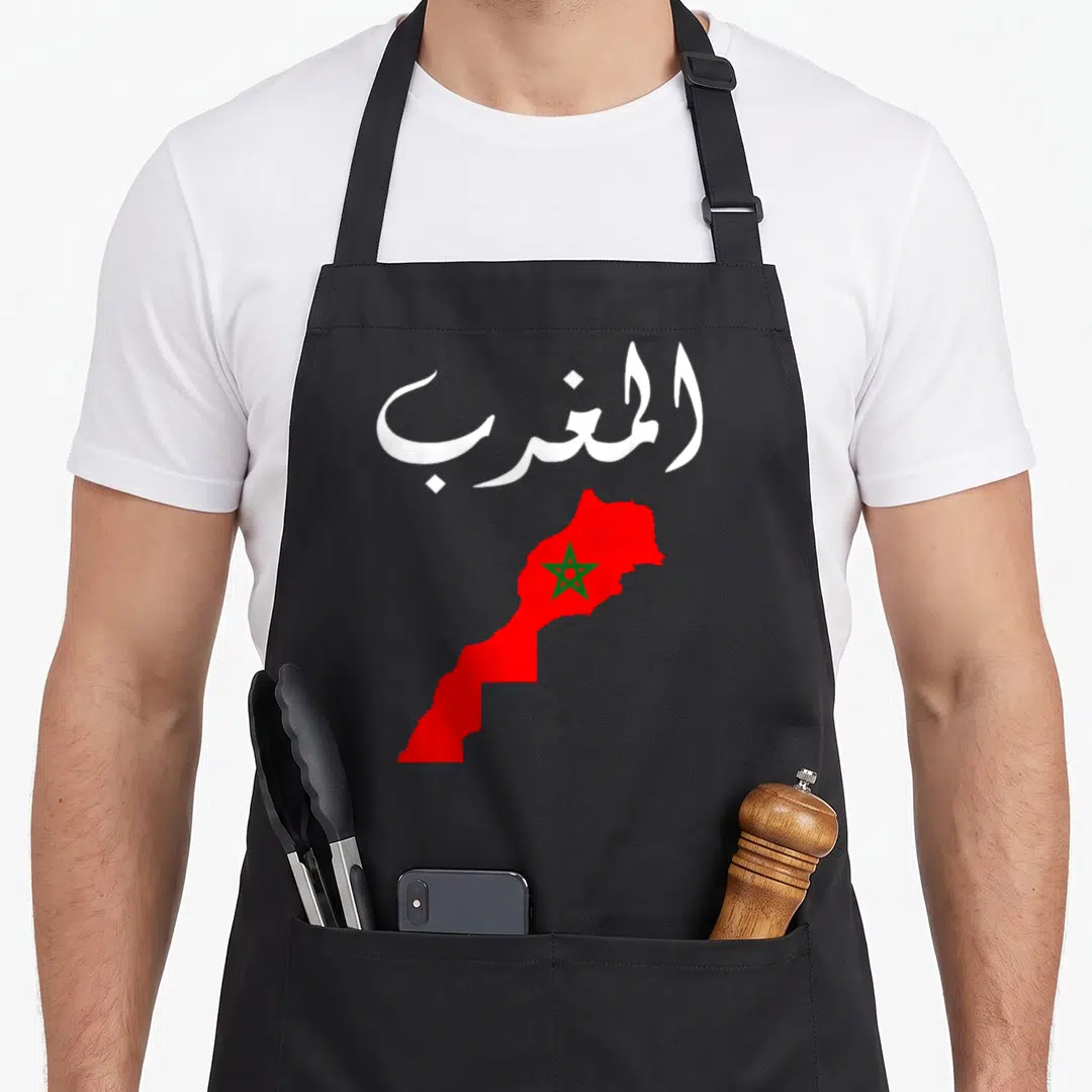 Morocco pride apron - White Arabic text above a red map of Morocco containing a green star — shown on a black cotton canvas apron against a white background