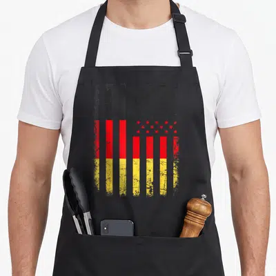 Germany american flag apron - Hybrid flag with black red yellow vertical stripes and distressed star field — shown on a black cotton canvas apron against a white background